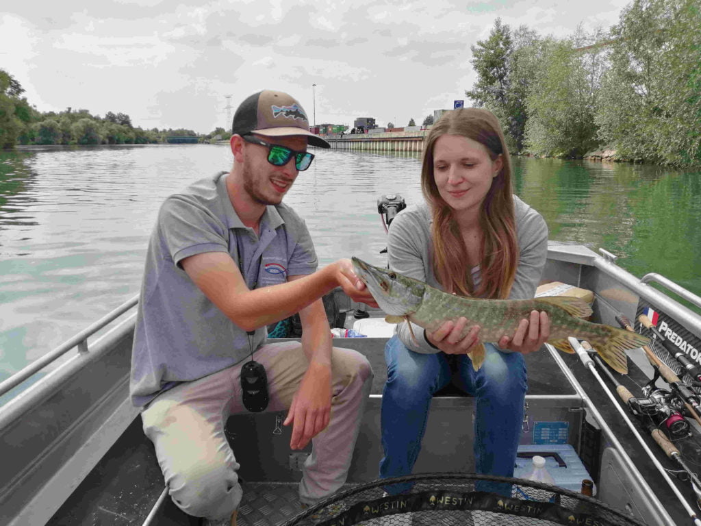 Une cliente heureuse avec un beau brochet lors d'une journée de guidage en bateau sur Seine